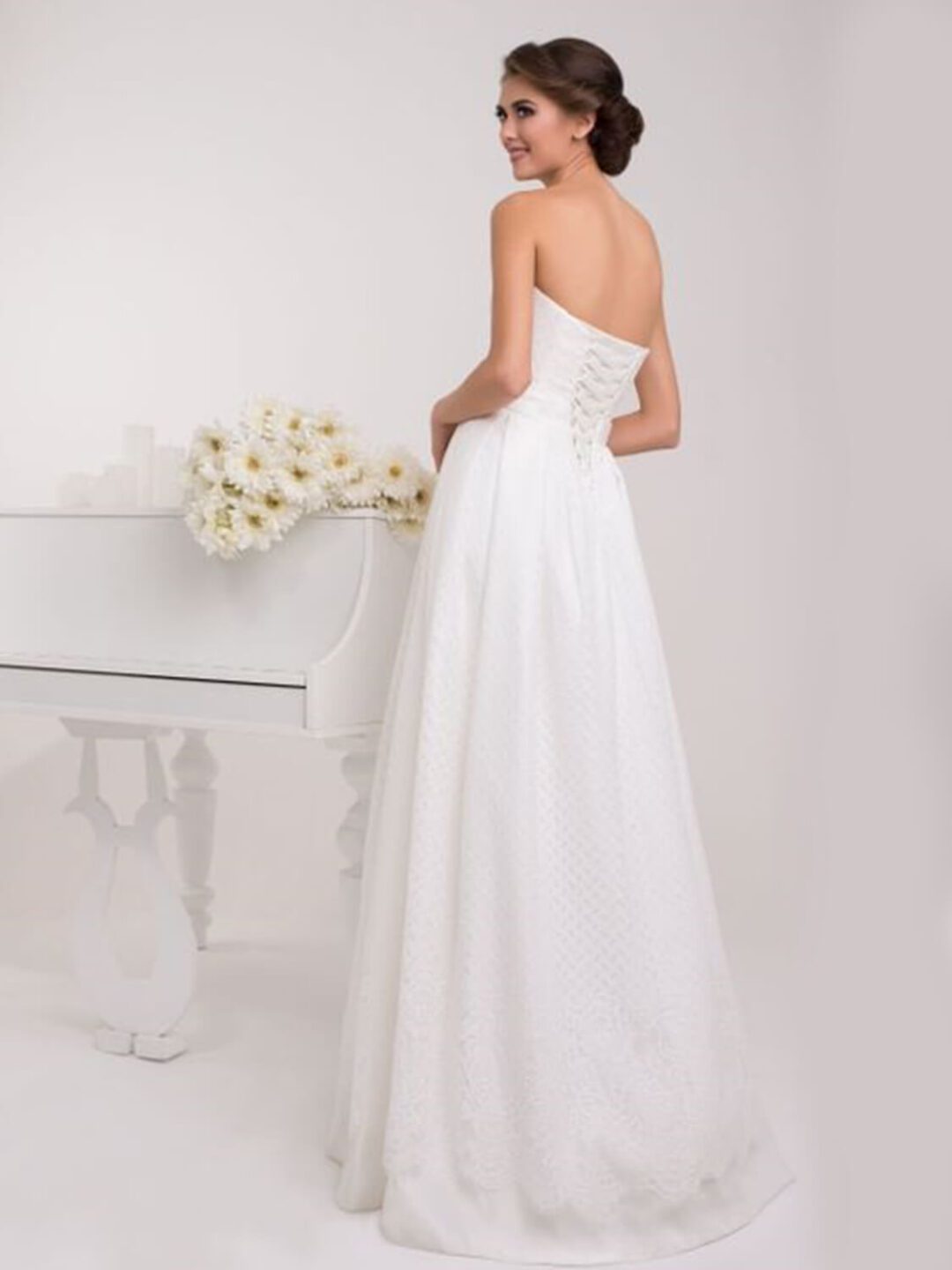 Στράπλες  νυφικό σε Άλφα γραμμή με υπέροχο δέσιμο στη μέση με πλούσιο φιόγκο. Σε ανάγλυφο γαλλικό σατέν. Υπέροχο δέσιμο με κορδέλα στην πλάτη σε στυλ κορσέ.