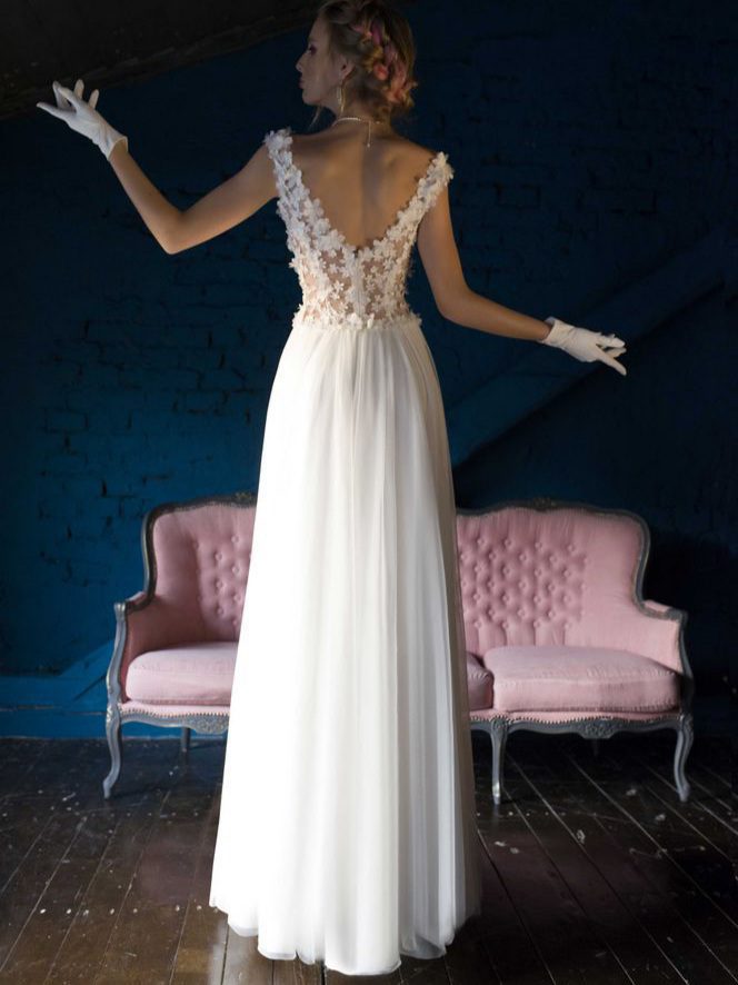 Μεταξωτό νυφικό σε ίσια γραμμή , με φούστα από μεταξωτή μουσελίνα. Με υπέροχο ολοκέντητο μπούστο με 3D μεταξωτά χειροποίητα λουλούδια, που καταλήγει σε βαθύ V στην πλάτη και το μπούστο. Αέρινη γραμμή. Ελληνικής ραφής