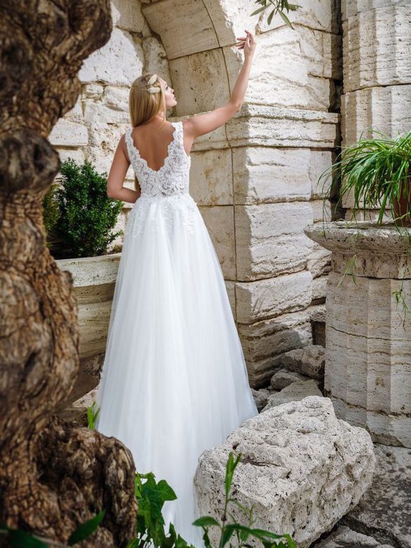 Ρομαντικό νυφικό σε Άλφα γραμμή, με φούστα από γαλλικό τούλι και κεντημένη δαντέλα κάτω από τη μέση. Με υπέροχο ολοκέντητο μπούστο με γαλλική δαντέλα που καταλήγει σε βαθύ V στην πλάτη και το μπούστο. Άνετη γραμμή. Ελληνικής ραφής
