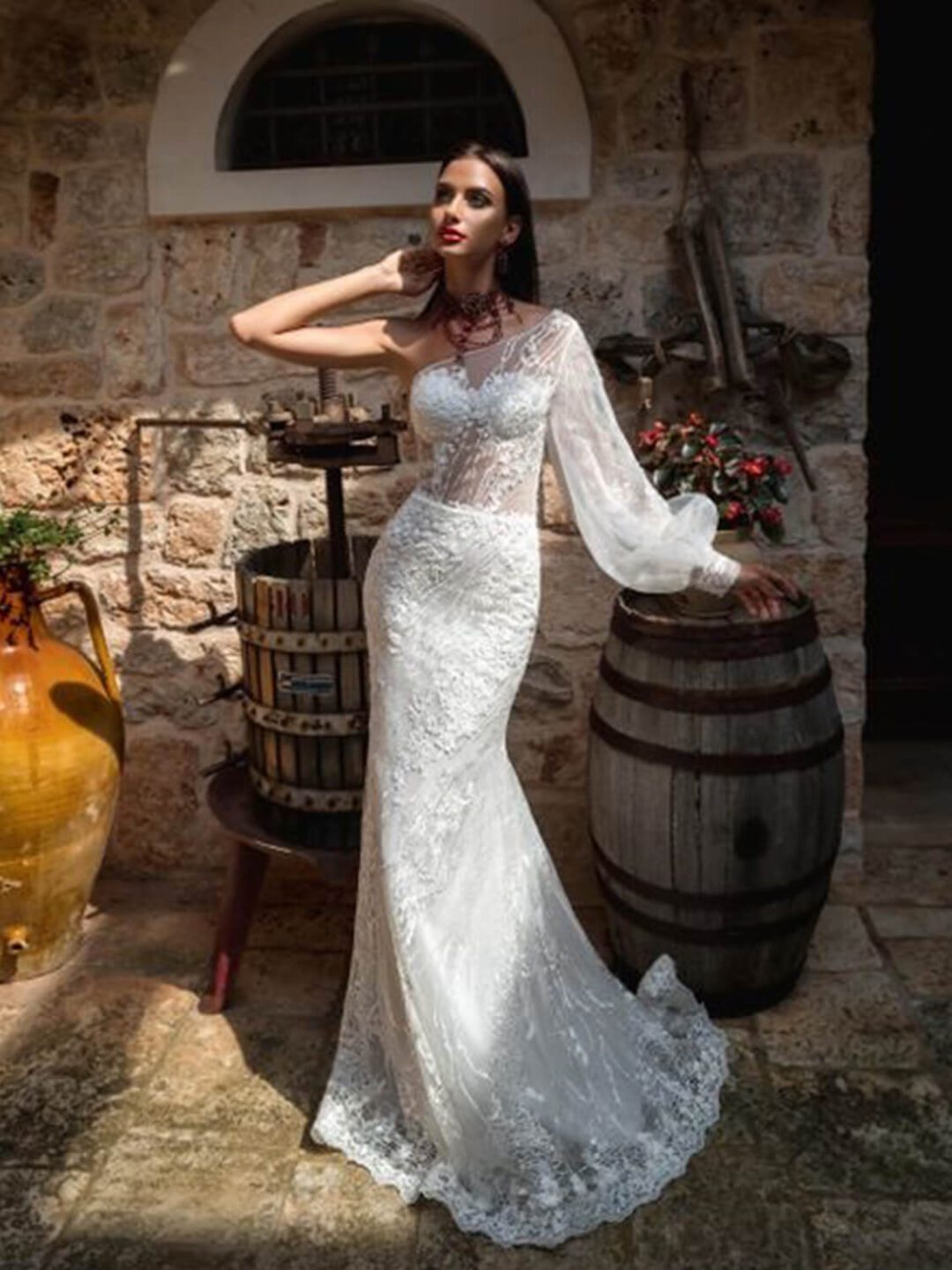 Γοργονέ νυφικό ολοκέντητο  με γαλλική δαντέλα και διαφάνεια soleil στο μπούστο, με έναν ώμο και φουσκωτό μανίκι δαντέλα. Φούστα γοργόνας με μακριά ουρά.