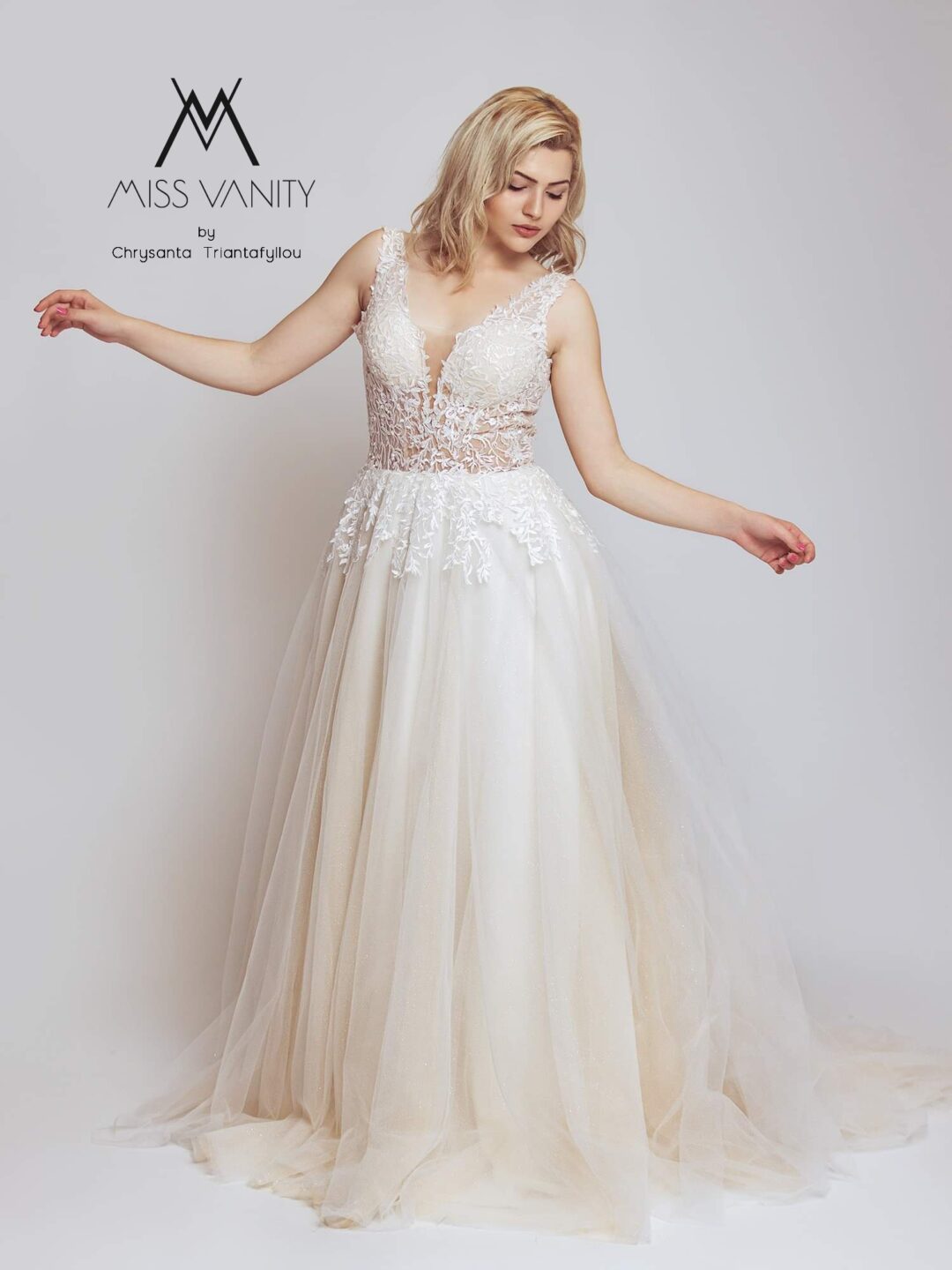 Εντυπωσιακό νυφικό με διαφάνεια στο μπούστο και κεντημένο με ανάγλυφη γαλλική δαντέλα. Φούστα σε άλφα γραμμή, από γαλλικό τούλι σε λευκό με νερά στο χρώμα της πούδρας. Ανοιχτή πλάτη σε βαθύ V. 